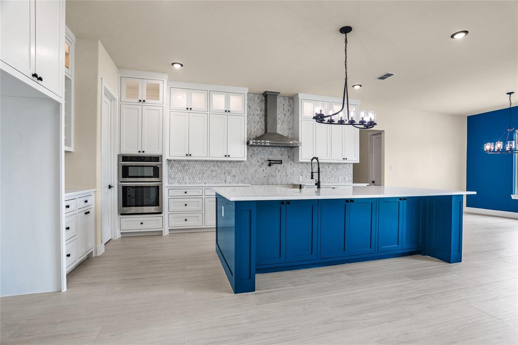 7637 County Road 1052 Celeste, TX 75423 - Photo 7 of 40 Kitchen with a chandelier, wall chimney exhaust hood, stainless steel double oven, light wood-style flooring, and tasteful backsplash