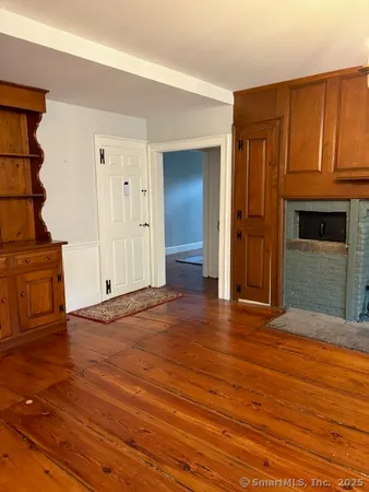 a view of an empty room with wooden floor and a fireplace