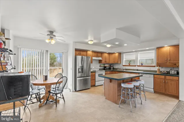 a kitchen with stainless steel appliances granite countertop table chairs stove and refrigerator