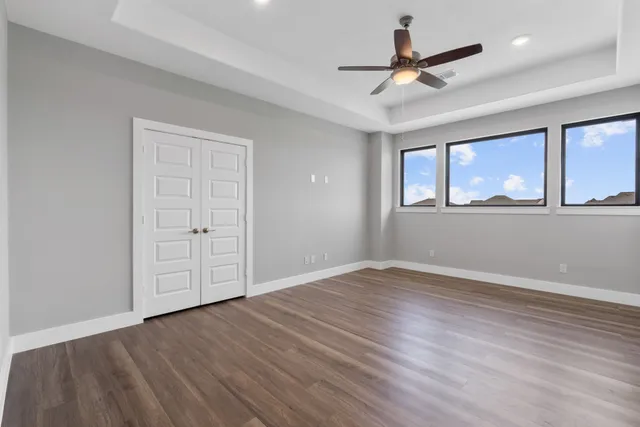 a view of empty room with wooden floor and fan