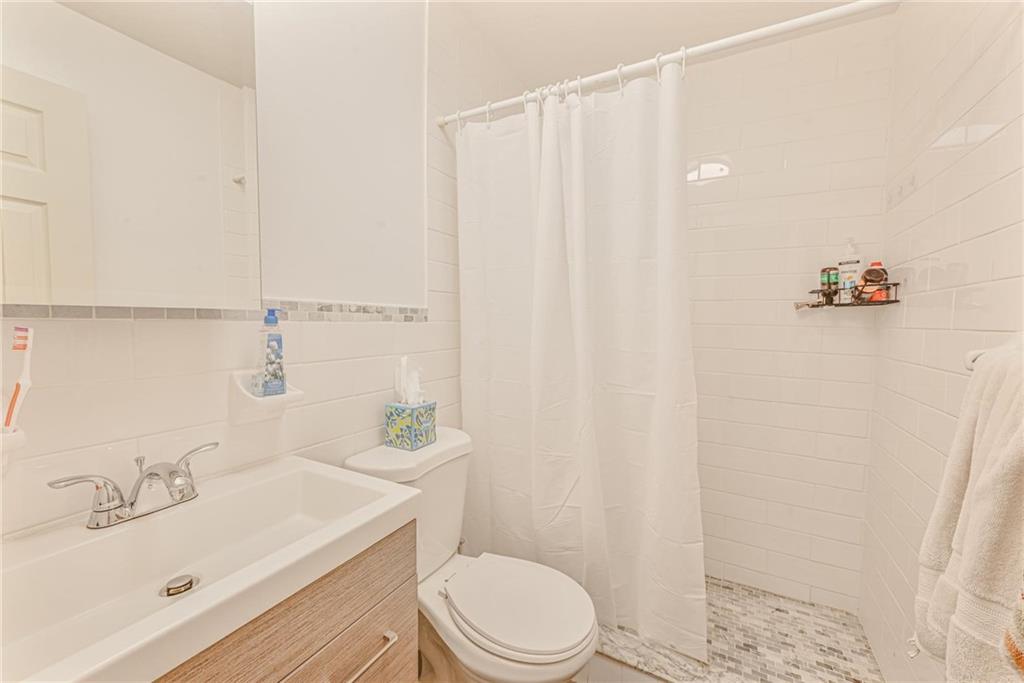 1237 82nd Street Brooklyn, NY 11228 - Photo 18 of 24 a bathroom with a sink a toilet and shower curtain