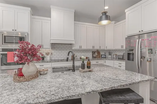 a kitchen with stainless steel appliances granite countertop a sink refrigerator and microwave
