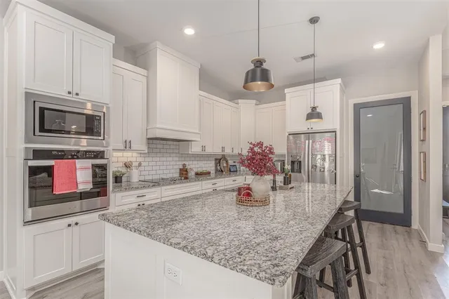 a kitchen with kitchen island granite countertop a table chairs sink and cabinets