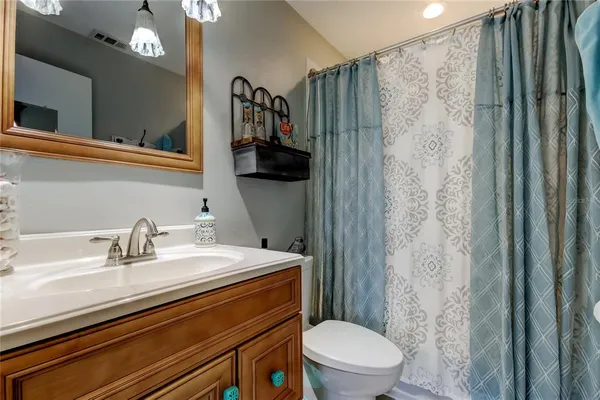 a bathroom with a granite countertop sink a toilet a mirror and shower