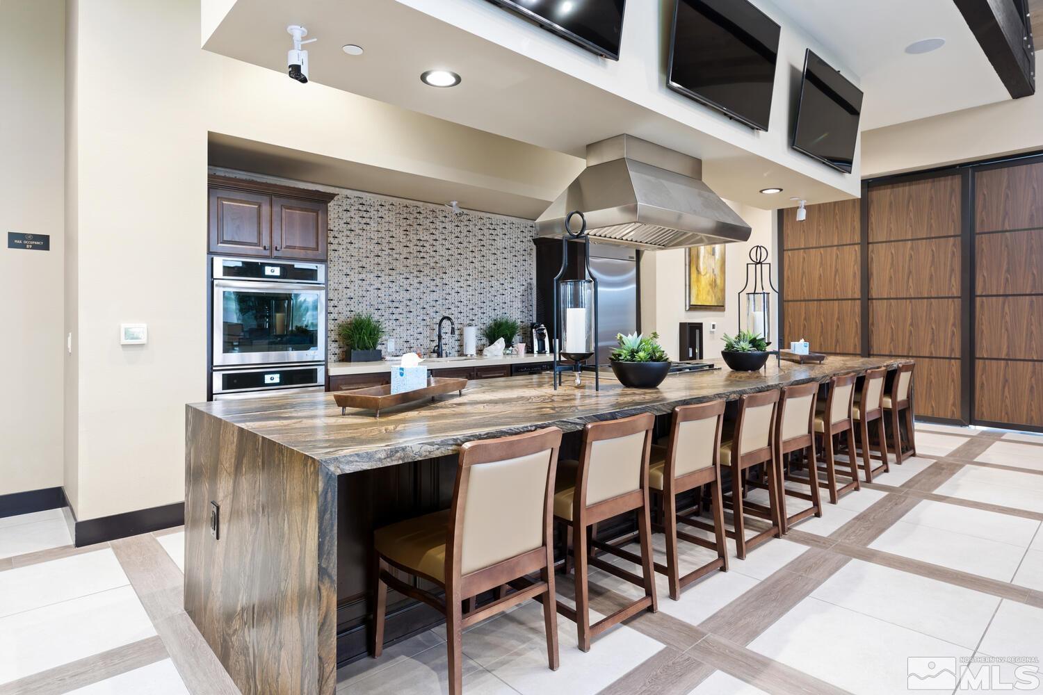 9775 Thesolious Lane Reno, NV 89521 - Photo 37 of 40 a kitchen with stainless steel appliances kitchen island granite countertop a table chairs sink and cabinets
