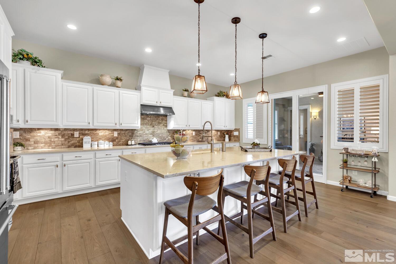 9775 Thesolious Lane Reno, NV 89521 - Photo 6 of 40 a kitchen with stainless steel appliances kitchen island granite countertop a table chairs and white cabinets