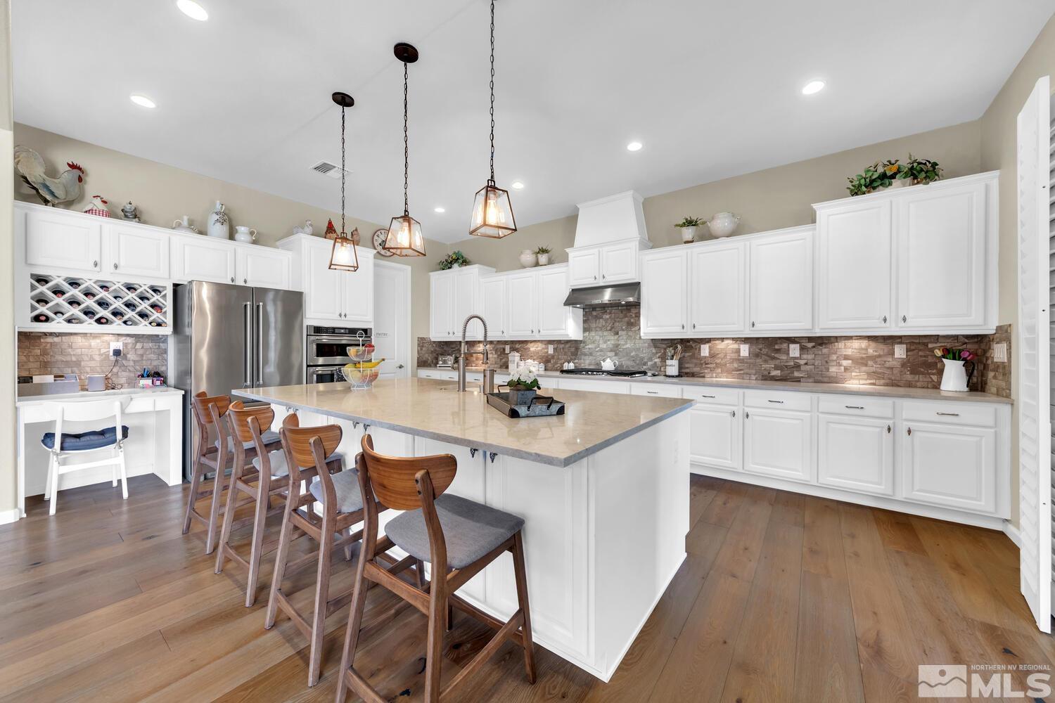 9775 Thesolious Lane Reno, NV 89521 - Photo 8 of 40 a kitchen with stainless steel appliances kitchen island granite countertop a stove a sink a refrigerator and white cabinets with wooden floor