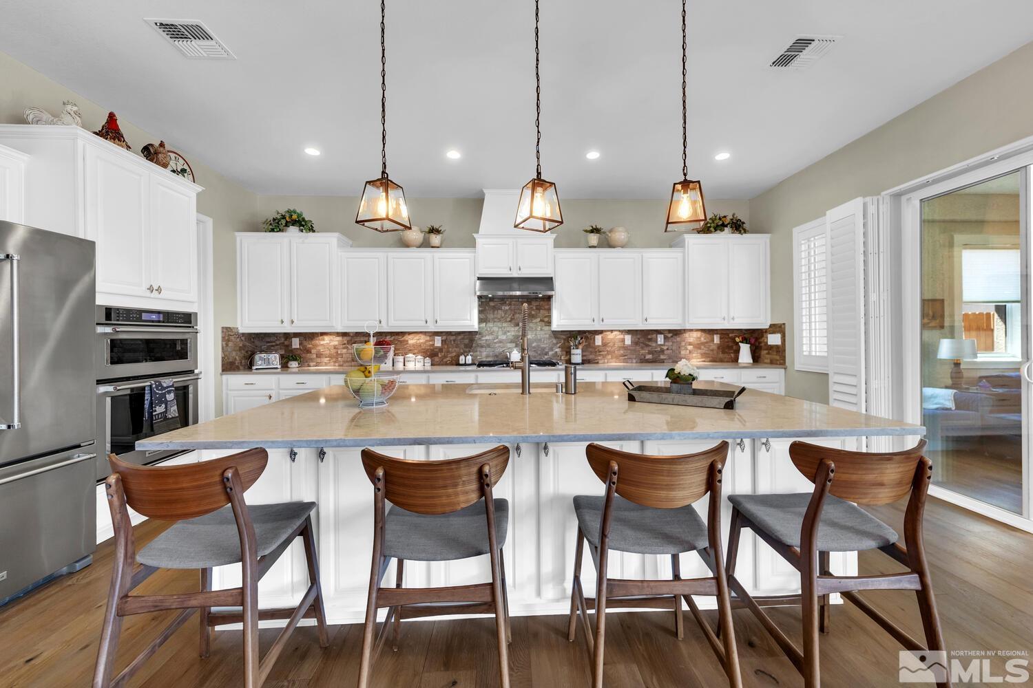 9775 Thesolious Lane Reno, NV 89521 - Photo 9 of 40 a kitchen with a dining table chairs wooden floor and appliances