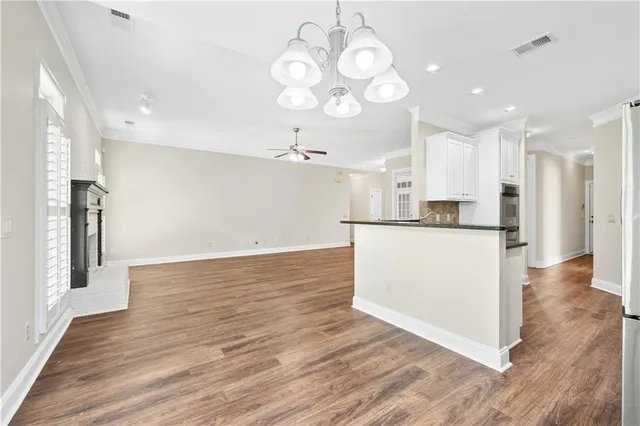 a view of kitchen and empty room with wooden floor