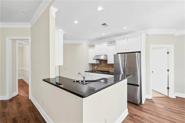 a kitchen with kitchen island a refrigerator stove and wooden floor