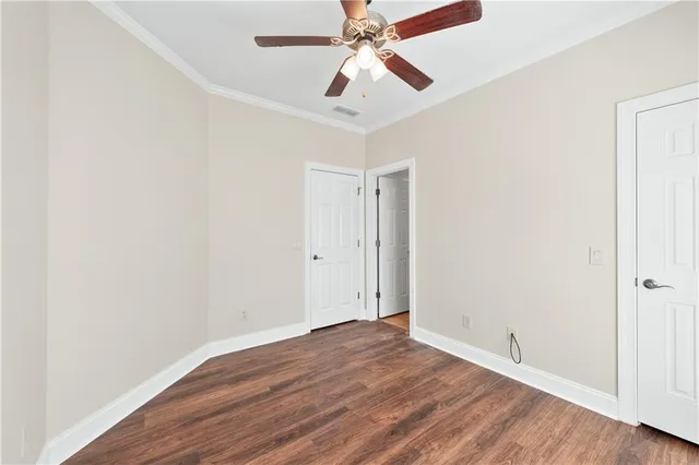 an empty room with wooden floor ceiling fan and windows