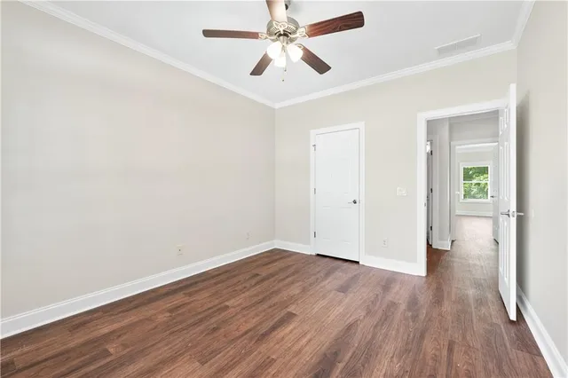 an empty room with wooden floor ceiling fan and windows