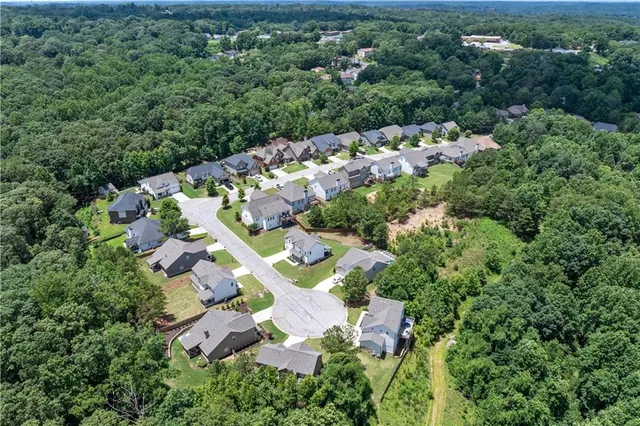 an aerial view of residential house with outdoor space and trees all around