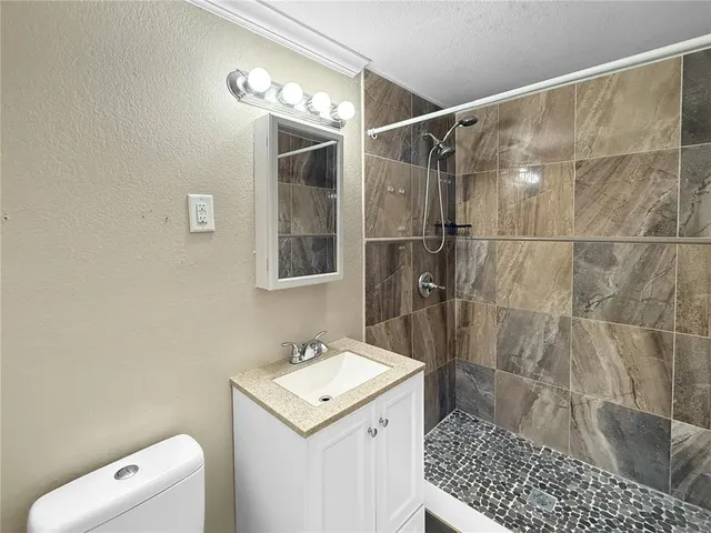 a bathroom with a sink a toilet and shower