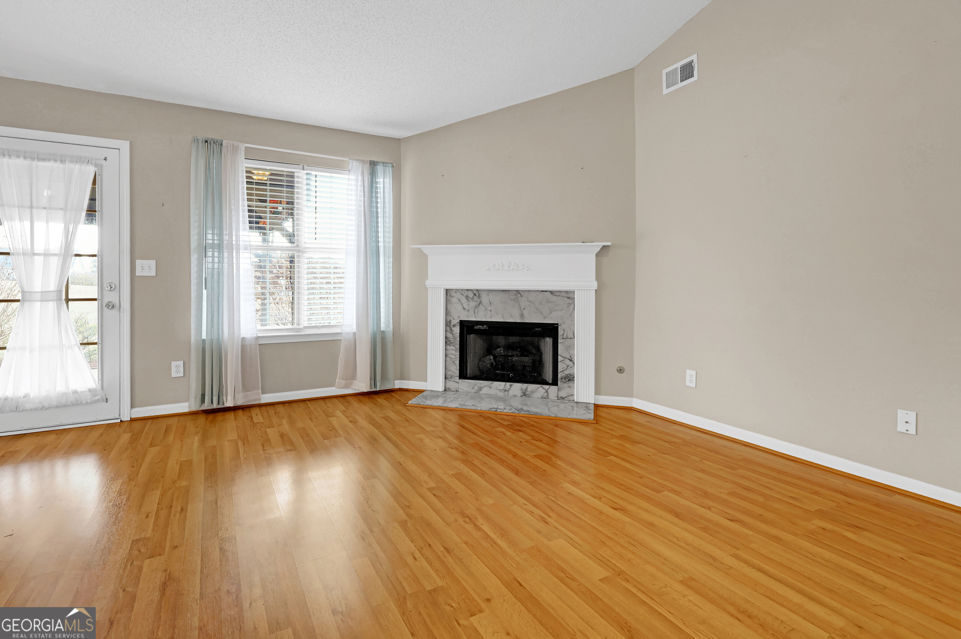 313 Harris Avenue Locust Grove, GA 30248 - Photo 29 of 34 wooden floor fireplace and windows in an empty room
