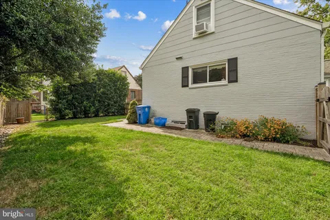 a backyard of a house with plants and large tree