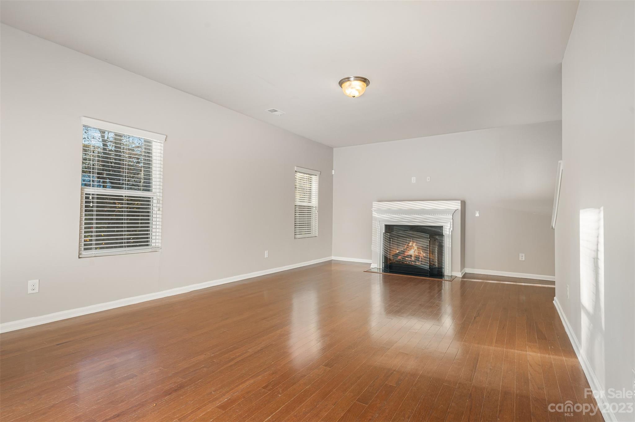 13225 Chelsea Ridge Lane Huntersville, NC 28078 - Photo 6 of 40 an empty room with wooden floor fireplace and windows