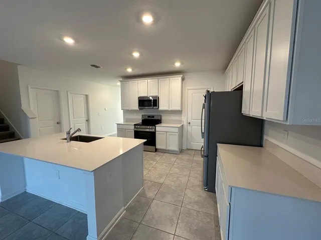 a kitchen with a refrigerator a stove top oven and a sink