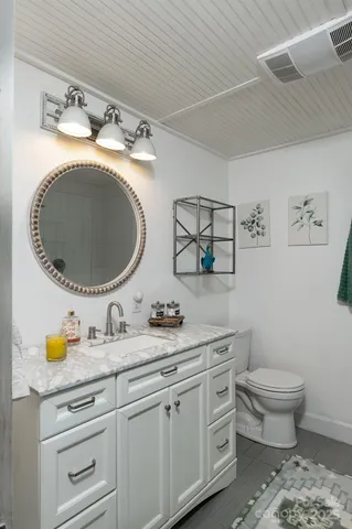 a bathroom with a granite countertop toilet sink and mirror