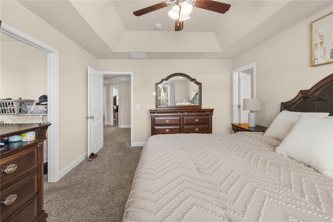 874 Wild Orchard Lane Woodruff, SC 29388 - Photo 13 of 35 This spacious bedroom features a tray ceiling and plush carpet flooring for comfort and elegance.