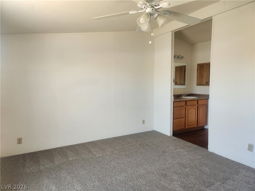 3189 Del Monte Street Laughlin, NV 89029 - Photo 14 of 32 A comfortable bedroom features plush carpeting and a ceiling fan, offering direct access to an attached bathroom.