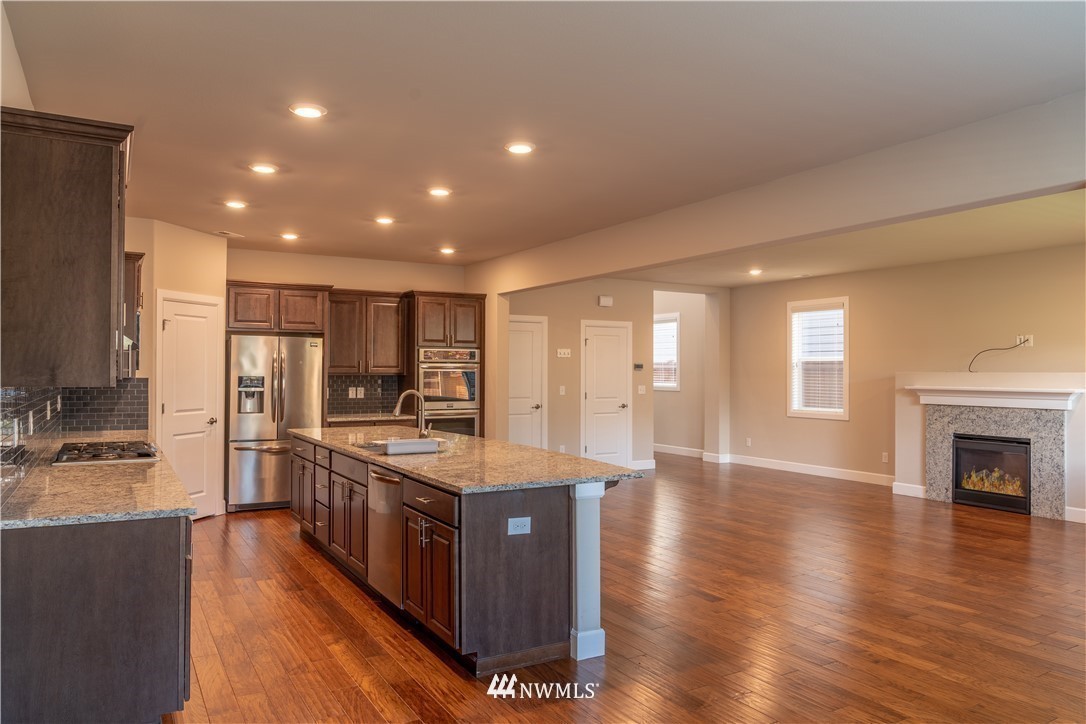 17317 40th Avenue Southeast Bothell, WA 98012 - Photo 5 of 24 a kitchen with stainless steel appliances granite countertop a stove top oven a sink dishwasher a refrigerator and a fireplace with wooden floor