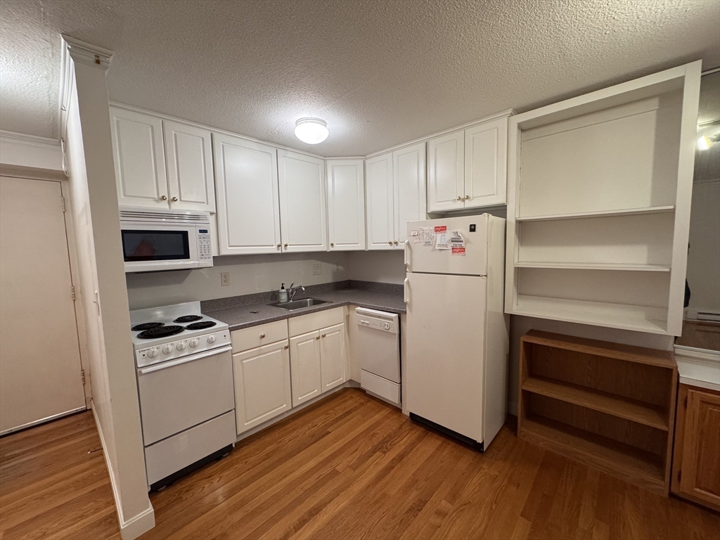 1691 Cambridge Street, Unit 22 Cambridge, MA 02138 - Photo 2 of 17 a kitchen with white cabinets and white appliances