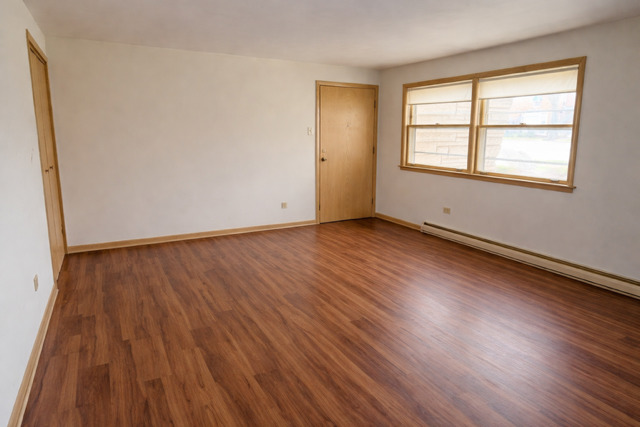 8304 W Forest, Unit 1W Chicago, IL 60634 - Photo 2 of 6 an empty room with wooden floor and windows