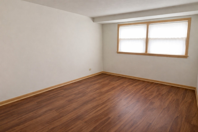 8304 W Forest, Unit 1W Chicago, IL 60634 - Photo 4 of 6 a view of an empty room with wooden floor and a window