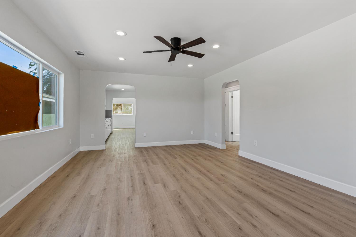 12484 South Union Road Manteca, CA 95336 - Photo 6 of 38 an empty room with wooden floor a ceiling fan and windows
