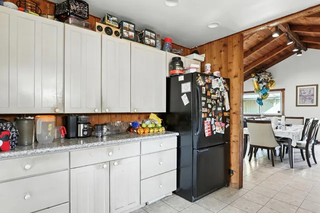 a kitchen with stainless steel appliances kitchen island granite countertop a refrigerator and a dining table