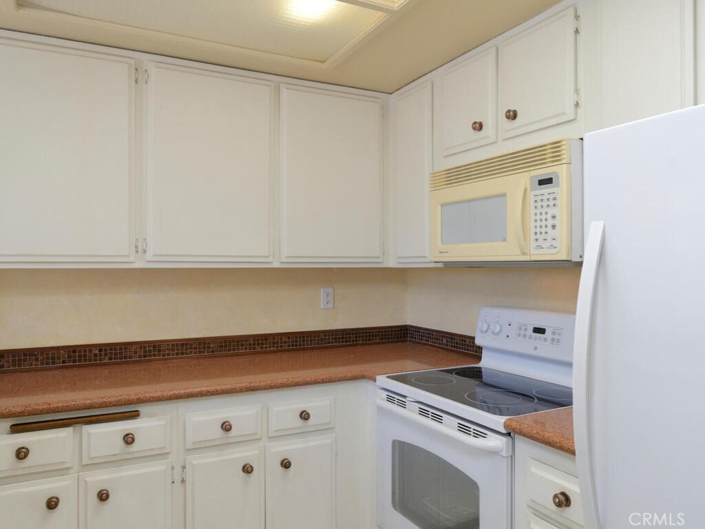 10074 Base Line Road Rancho Cucamonga, CA 91701 - Photo 5 of 18 a kitchen with granite countertop white cabinets and white appliances