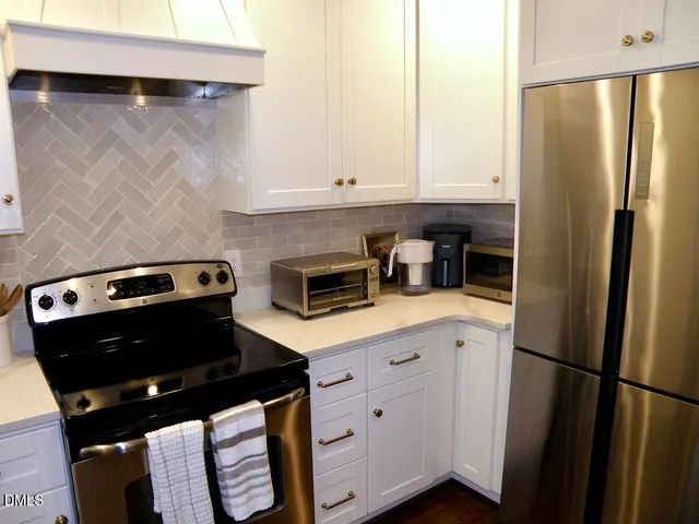 a kitchen with a refrigerator a stove and white cabinets