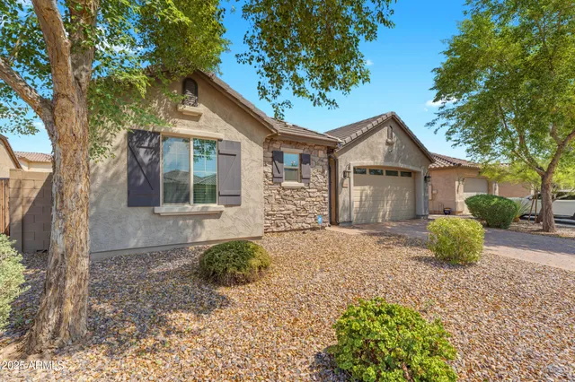 a front view of a house with a garden and trees