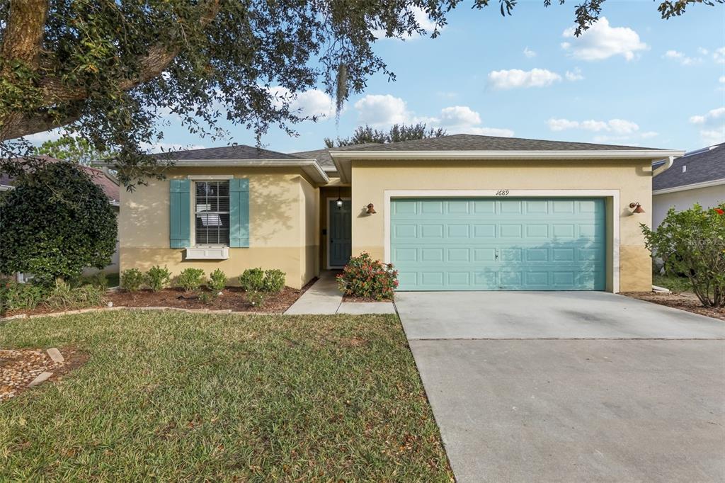 1689 Strathmore Circle Mount Dora, FL 32757 - Photo 2 of 37 front view of a house with a yard and potted plants