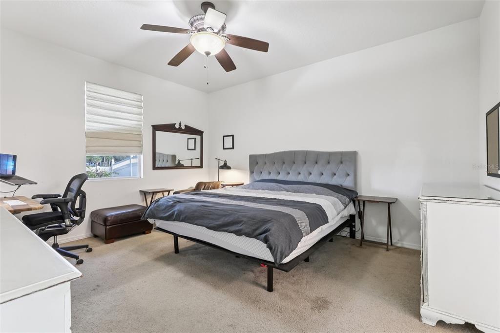 1689 Strathmore Circle Mount Dora, FL 32757 - Photo 24 of 37 a spacious bedroom with a bed and a chandelier