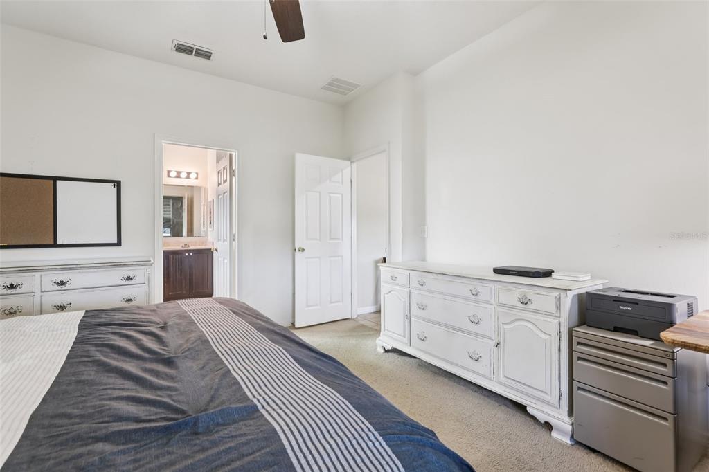 1689 Strathmore Circle Mount Dora, FL 32757 - Photo 26 of 37 a spacious bedroom with a bed and a flat tv screen on the dresser