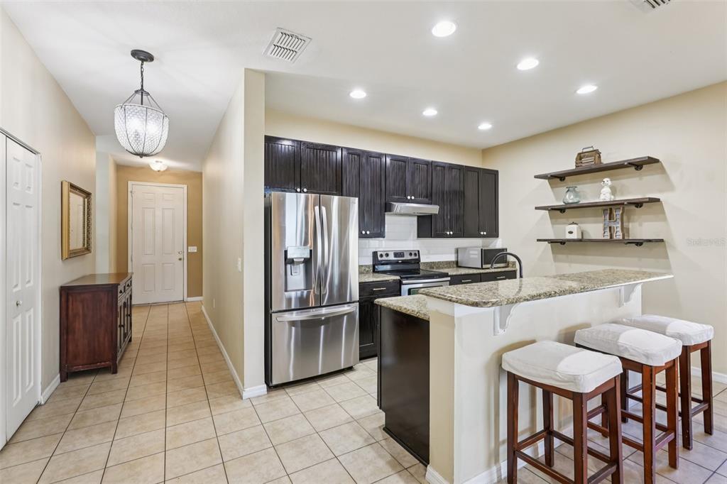 1689 Strathmore Circle Mount Dora, FL 32757 - Photo 8 of 37 a kitchen with stainless steel appliances a refrigerator a stove a sink dishwasher a dining table and chairs with wooden floor