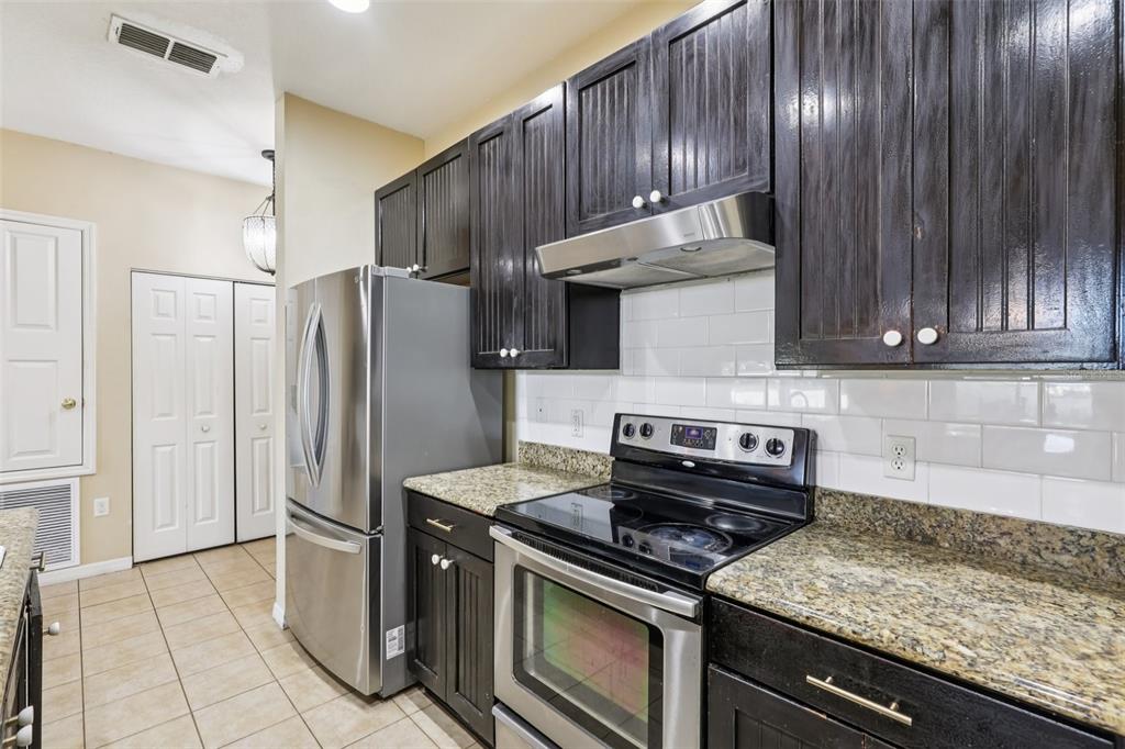 1689 Strathmore Circle Mount Dora, FL 32757 - Photo 10 of 37 a kitchen with stainless steel appliances granite countertop wooden cabinets a sink and a stove
