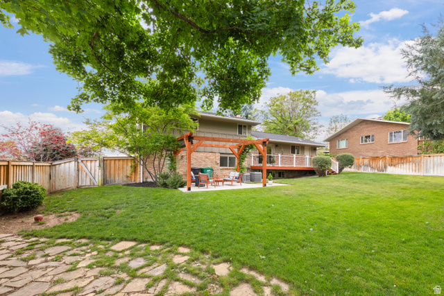 3320 Cherokee Lane Provo, UT 84604 - Photo 45 of 52 Expansive backyard featuring a manicured lawn, a flagstone patio, a wood pergola, a raised wood deck with white railings, and mature perimeter trees