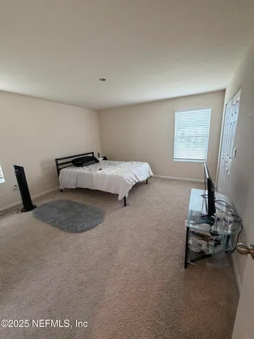 a bedroom with a bed and a flat tv screen on a dresser