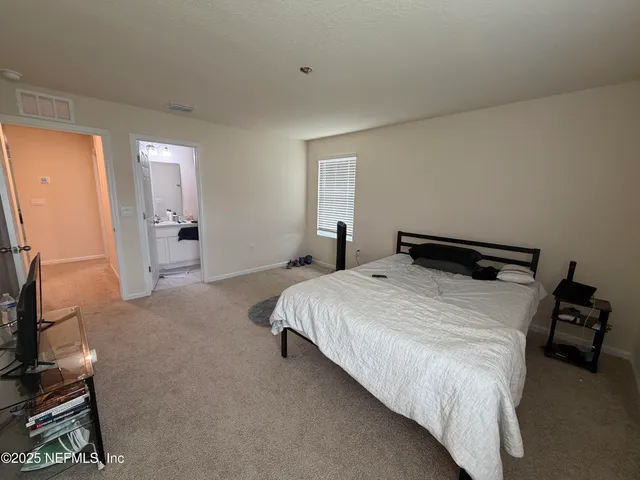 a bedroom with a bed and a flat tv screen on the dresser