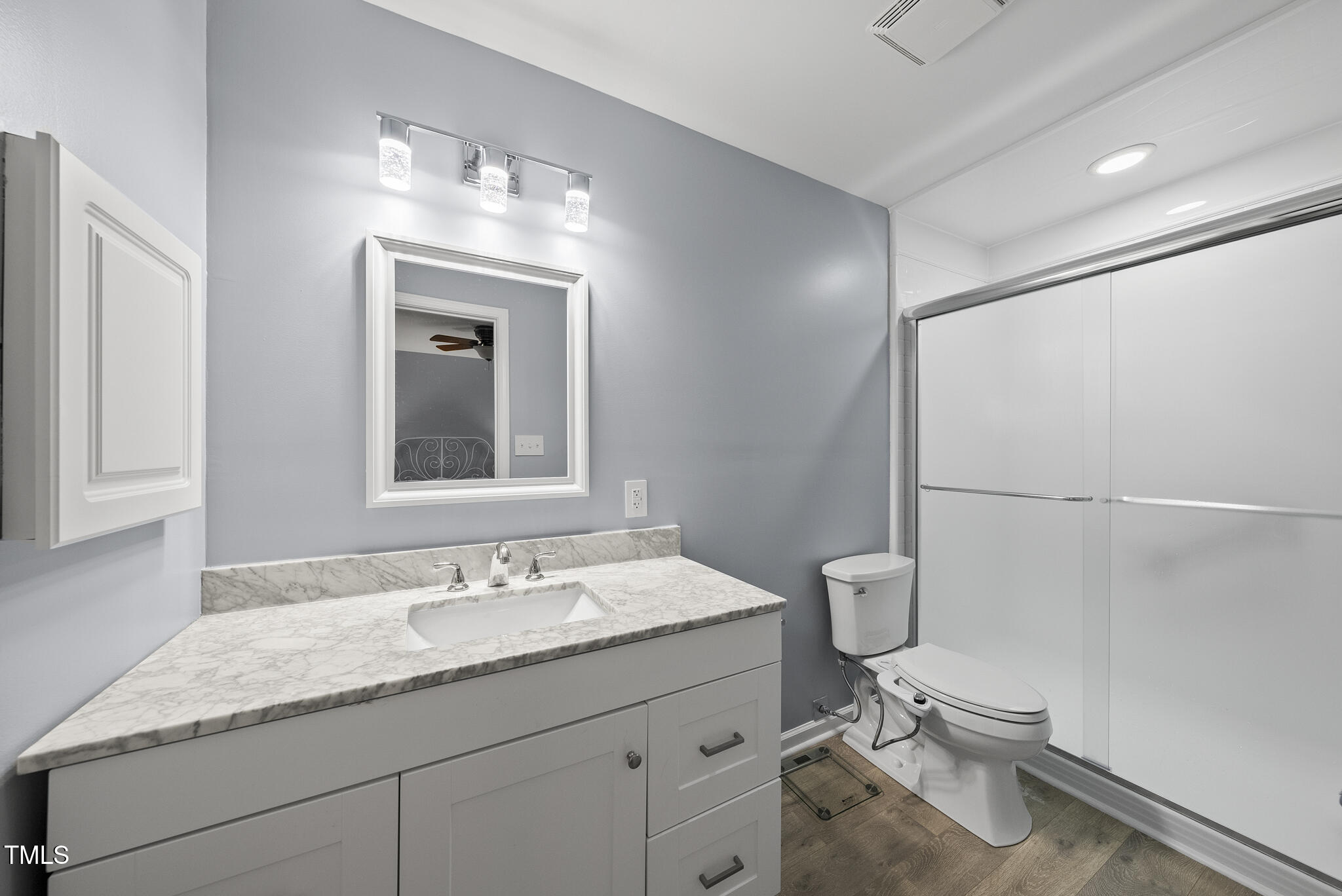 8613 Lobelia Street Raleigh, NC 27603 - Photo 21 of 25 a bathroom with a granite countertop sink a toilet and a mirror