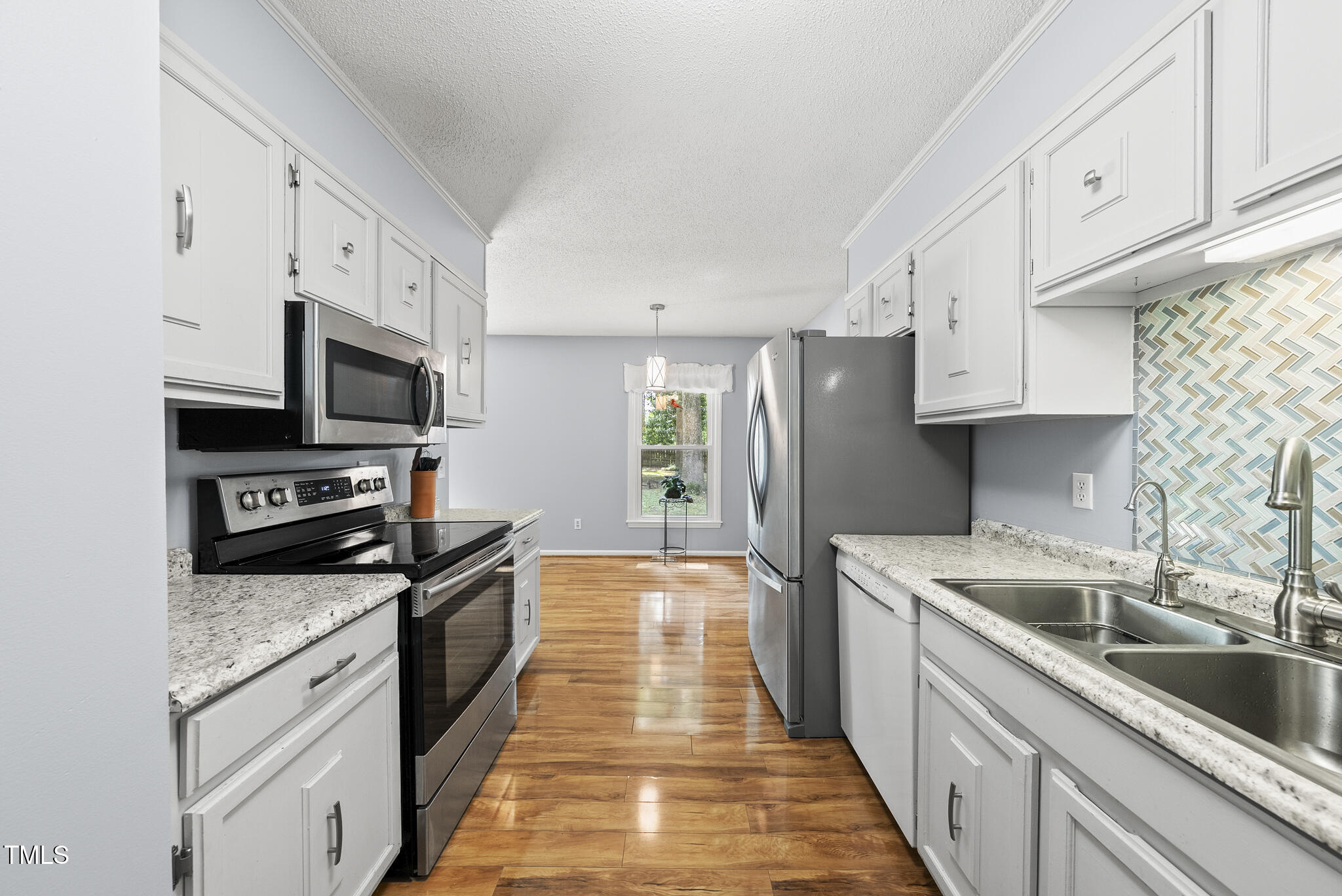 8613 Lobelia Street Raleigh, NC 27603 - Photo 8 of 25 a kitchen with stainless steel appliances granite countertop a sink stove microwave and refrigerator