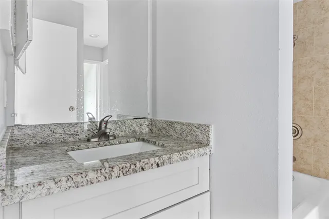 a bathroom with a granite countertop sink and a mirror