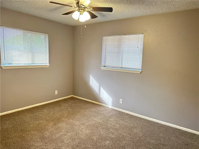 an empty room with a window and a fan