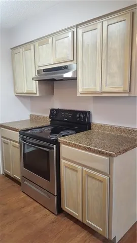a kitchen with granite countertop white cabinets and a stove with wooden floor
