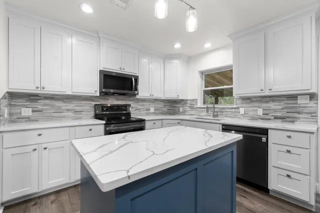 a kitchen with granite countertop white cabinets and stainless steel appliances
