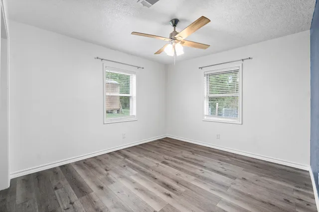a view of empty room with wooden floor and fan
