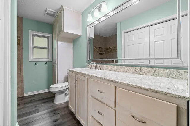 a bathroom with a granite countertop toilet and sink